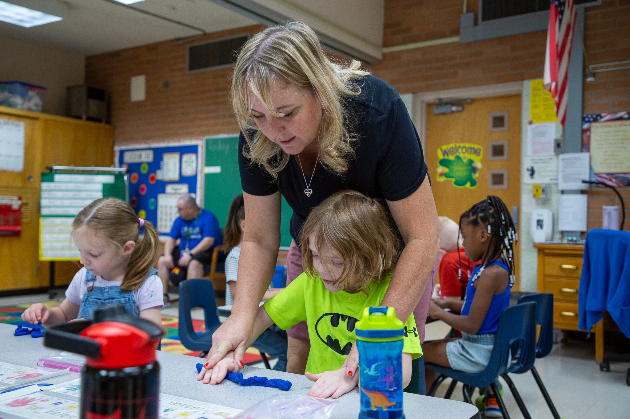 A teacher helps one of her students sculpt with blue playdoh