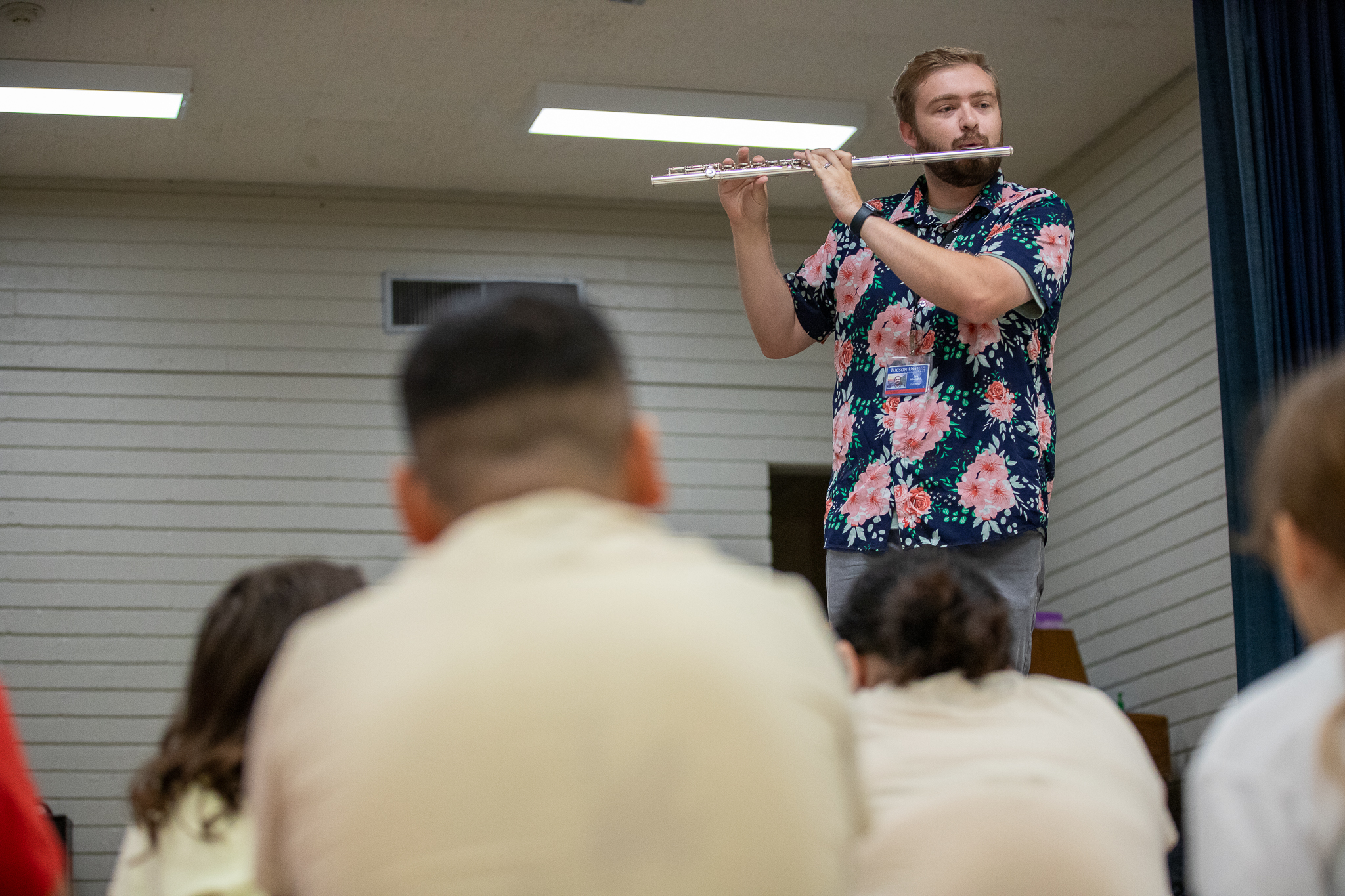 A teacher plays a flute for his students