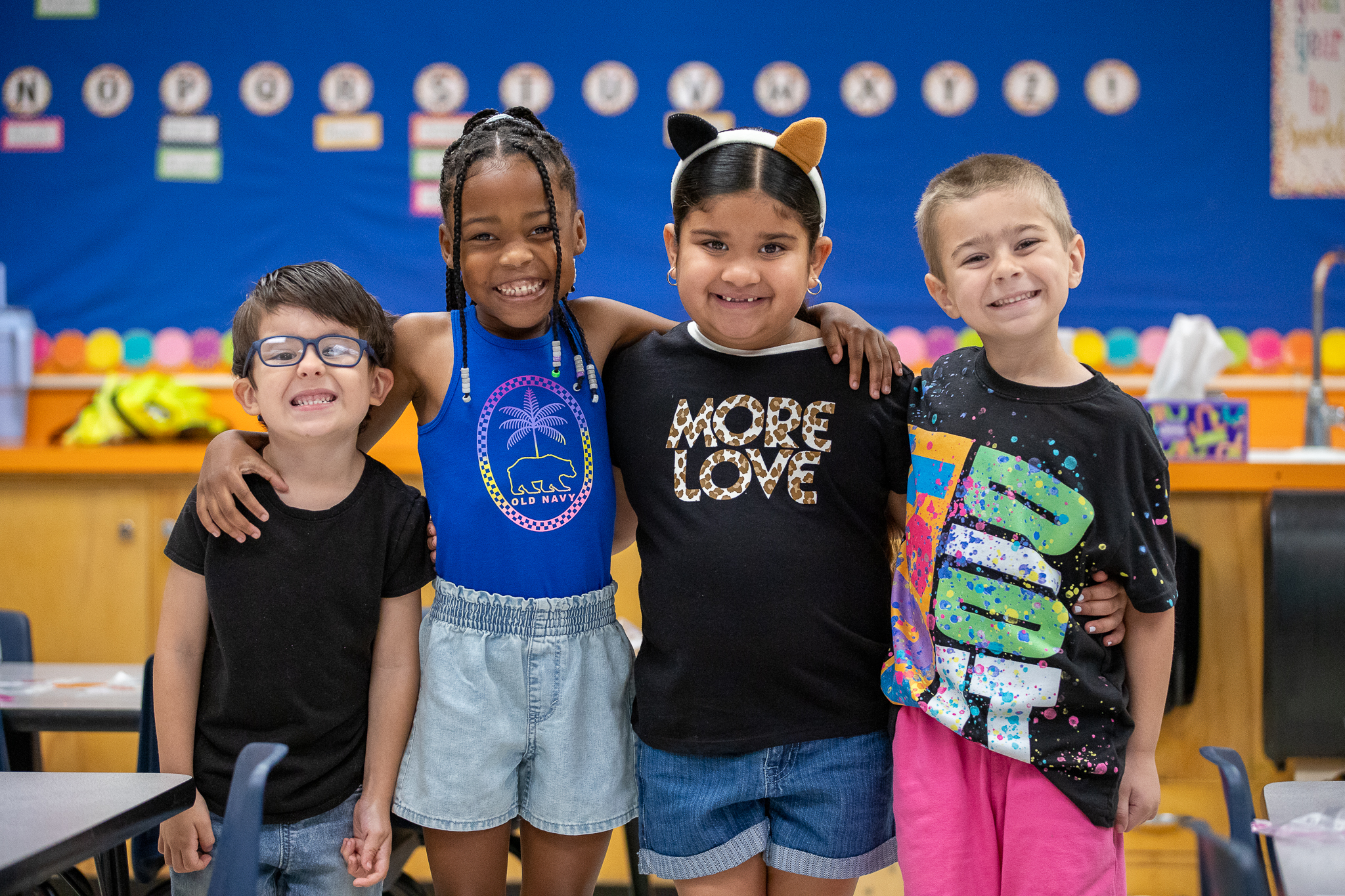 Four students smile together in the classroom