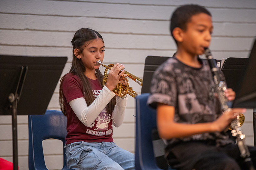 A girl, back, plays trumpet, and a boy, front, plays clarinet