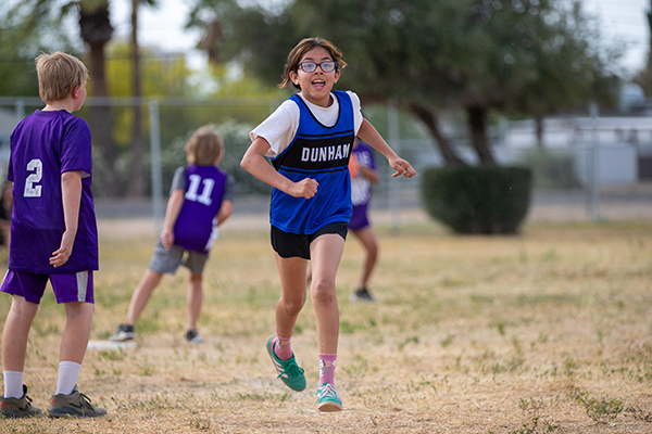 A girl runs excitedly across the field during the kickball game