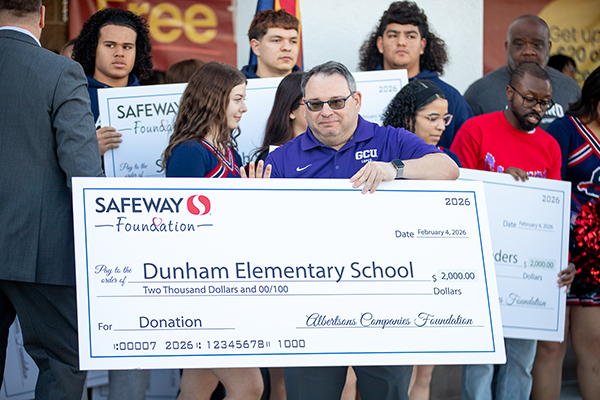 A man from Dunham holds up the school's giant check from the Safeway Foundation