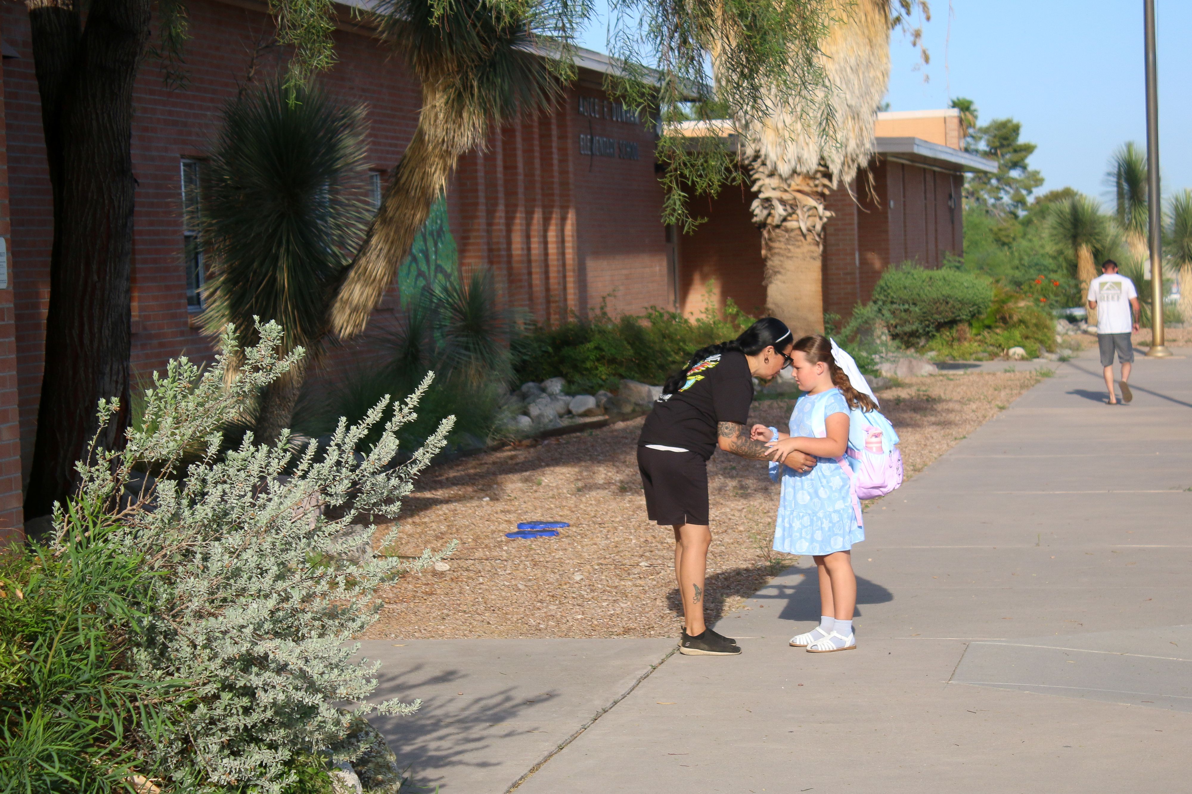 A mom hugs her daughter outside school