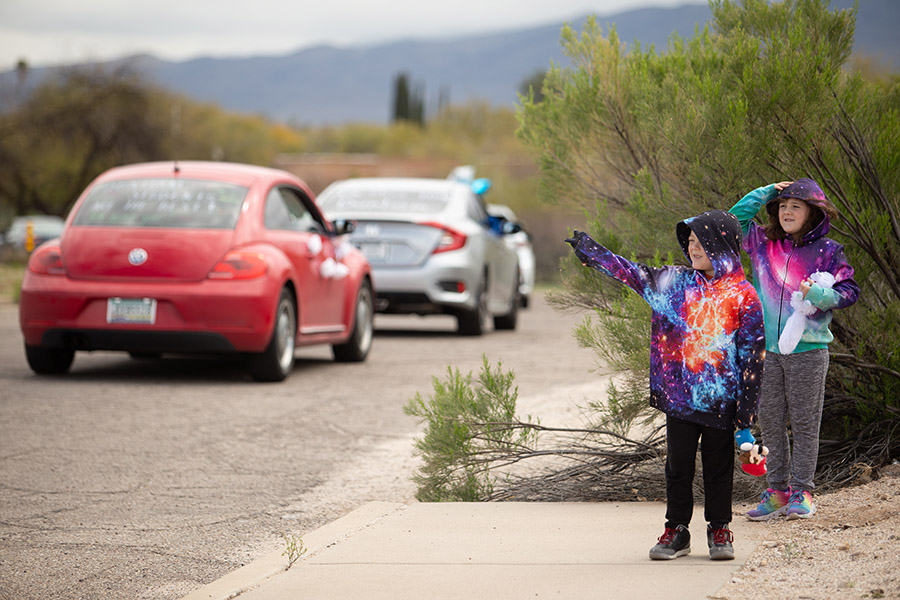 Two children waving at passing cars.